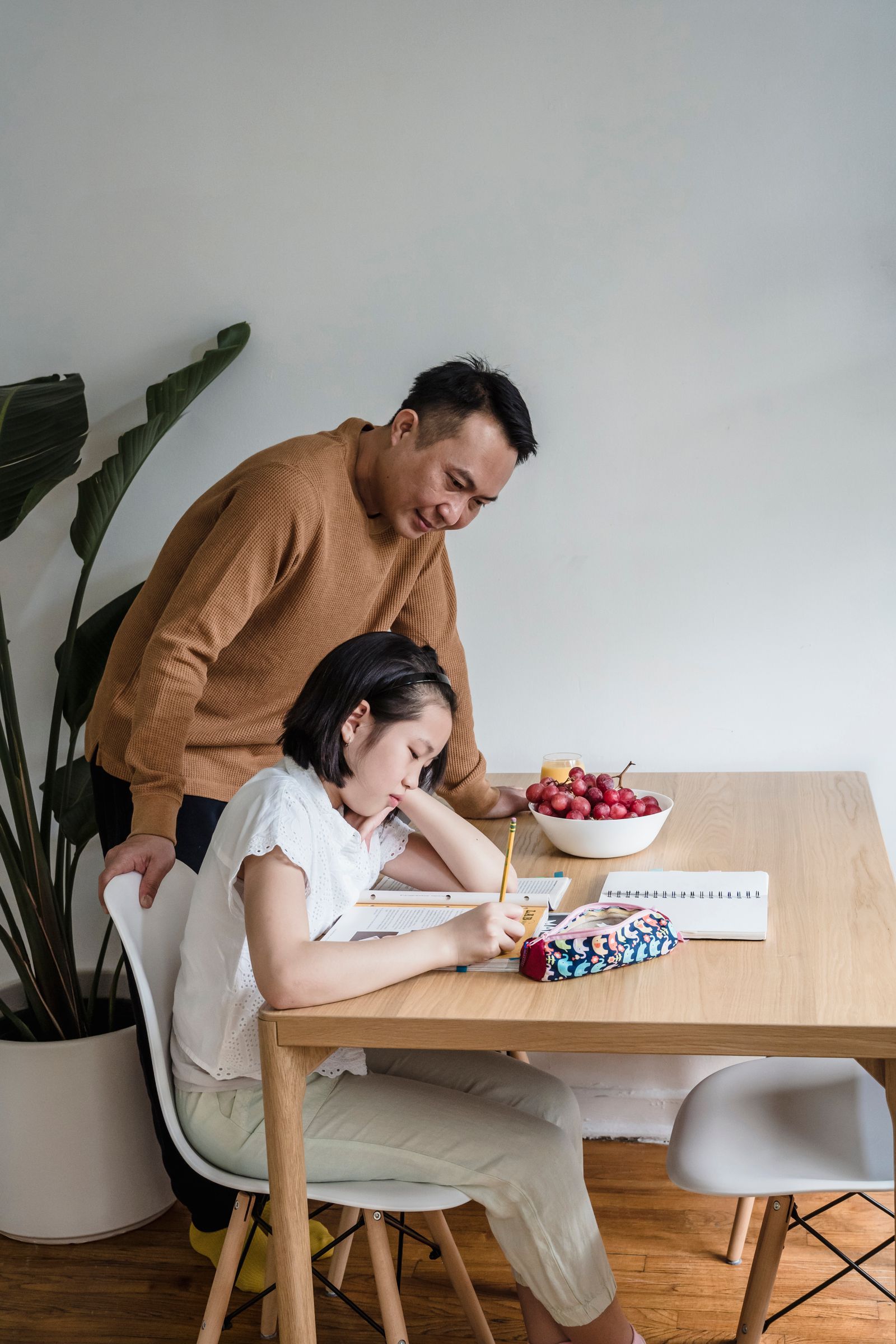 A father supporting his daughter while she studies at home